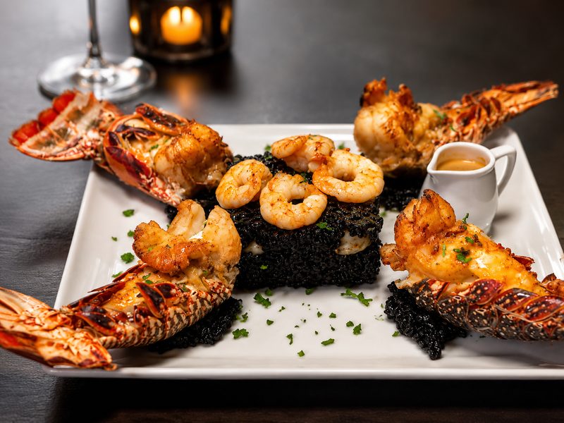 Lagosta e camarões sobre arroz negro, prato assinatura da Chef Saly